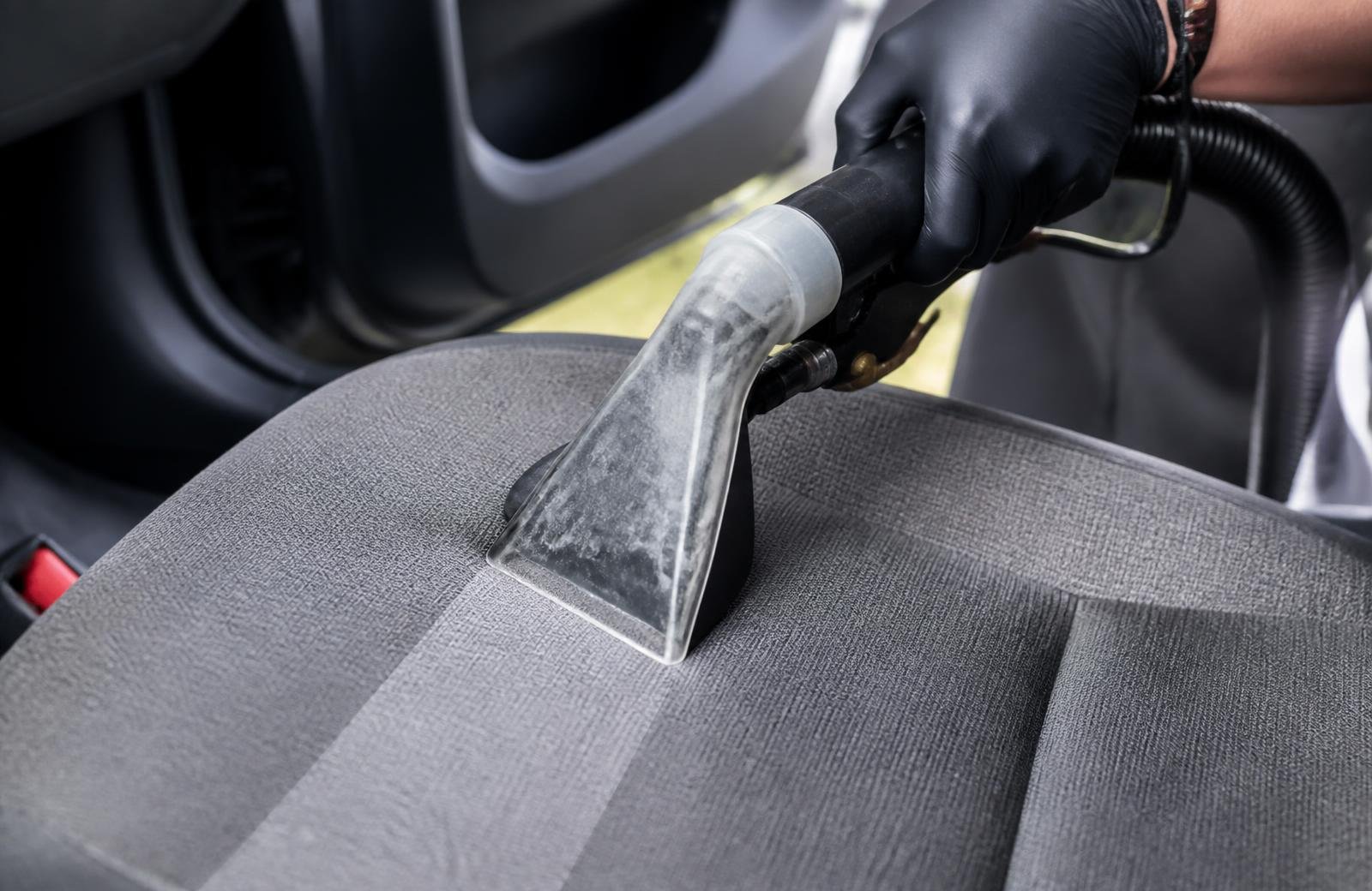 Buse d'injection-extraction professionnelle nettoyant l'assise en tissu gris d'un siège auto